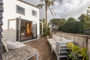 a patio with white furniture on a wooden deck at Tahana Villa - River View Retreat - 3 Bedroom in Oakura