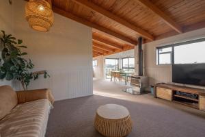 a living room with a couch and a flat screen tv at Tahana Villa - River View Retreat - 3 Bedroom in Oakura