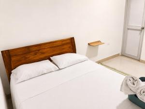 a bedroom with a white bed with a wooden headboard at La Casita Rooms - Habitaciones Coveñas in Coveñas