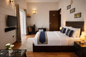 a hotel room with a large bed and a television at The Amber Signature Vrindavan # A Luxury Apartment With #Lift# Garden # Parking# Ac Rooms# & Elegant interior # Located Inside- Omaxe Eternity Vrindavan in Vrindāvan +9 photos
