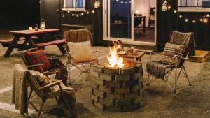 a fire pit in a room with chairs and a table at Gangneung Basecamp Pension in Gangneung +2 photos