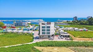 an aerial view of a white building with a parking lot at Gangneung Basecamp Pension in Gangneung