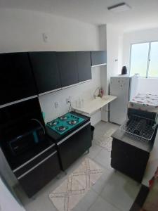 a kitchen with black cabinets and a stove top oven at Apartamento da Lagoa in Londrina