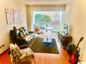 a living room with a leather couch and a guitar at Spacious Apartment in Miraflores in Lima