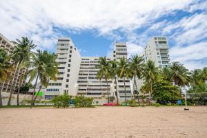 a beach with palm trees in front of a building at Beachfront Bliss at Isla Verde in San Juan