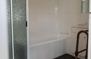 a white bathroom with a tub and a shower at White Shell Cottage - Woodfire & Beachfront in Falmouth