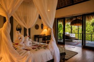 a bedroom with a canopy bed with swans on it at Villa Jasmine by Anakara in Ubud
