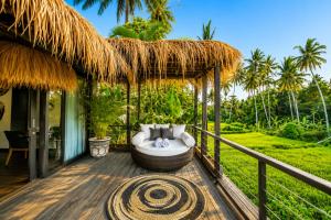 a patio with a couch on a deck at Villa Jasmine by Anakara in Ubud