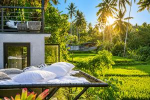 a bed with pillows on a patio with a garden at Villa Jasmine by Anakara in Ubud