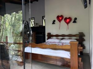 a bedroom with a bed with two hearts hanging on the wall at Chalé Carvalho in Araucária