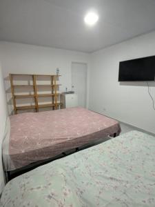 a bedroom with two beds and a television in it at Residencial Scarparo in Iguape