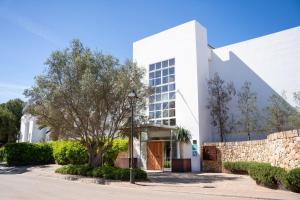 a white building with a tree in front of it at Meliá Cala d'Or Boutique Hotel in Cala d´Or