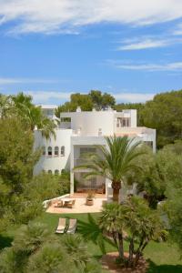 a white house with palm trees in front of it at Meliá Cala d'Or Boutique Hotel in Cala d´Or