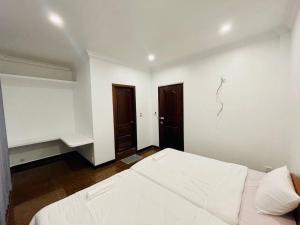 a white bedroom with a bed and two doors at Peace And Cool Hotel in Siem Reap +2 photos