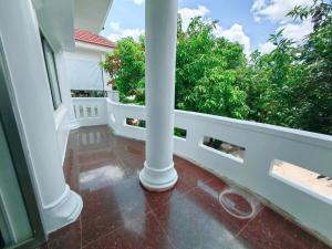 a balcony with a white column and trees at Peace And Cool Hotel in Siem Reap