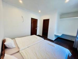 a white bed in a room with two doors at Peace And Cool Hotel in Siem Reap