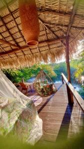 a wooden deck with a straw roof and a swing at Casa da Arvore Experiencia com cafe da manha e ar condicionado in Santarém