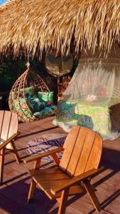 a deck with two chairs and a thatch roof at Casa da Arvore Experiencia com cafe da manha e ar condicionado in Santarém