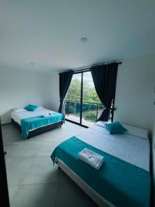 two beds in a room with a large window at BLUE DAYS Hotel Melgar in Melgar