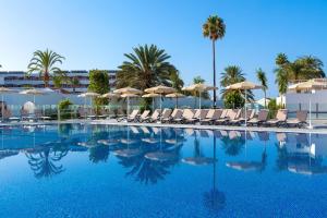 a swimming pool with chairs and umbrellas and palm trees at SOL by Meliá Barbacan in Playa del Ingles