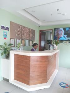 una donna in piedi al bancone della reception di un salone di Shore Time Dormitel a Boracay