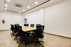 a conference room with a wooden table and black chairs at Super townhouse moosapet Rcc Prime in Hyderabad