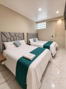 a bedroom with two beds with green and white sheets at Libertad Grand Hotel in Ayacucho