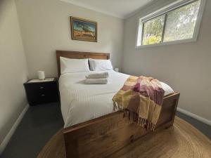 a bedroom with a large bed with white sheets and a window at Riverfront, Tiny Home in Natural Bush in Bridgetown
