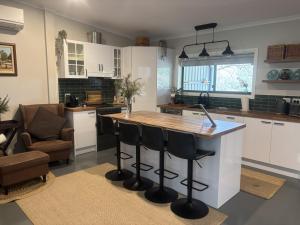 a kitchen with a island with bar stools at Riverfront, Tiny Home in Natural Bush in Bridgetown