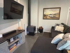 a living room with a couch and a flat screen tv at Riverfront, Tiny Home in Natural Bush in Bridgetown +41 photos