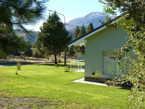 una casa con un patio verde con montañas al fondo en Altos de Ayelen, en Esquel