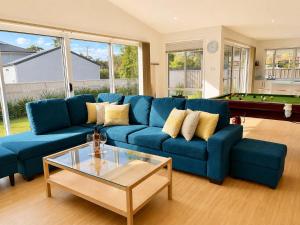 a living room with a blue couch and a pool table at The Coastal Haven in Manyana