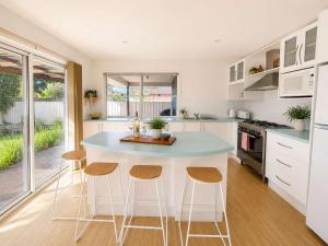 a kitchen with a blue counter and stools at The Coastal Haven in Manyana
