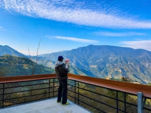 a woman holding a baby standing on a balcony overlooking mountains at Homestay 26 Cơ Sở 2 Tà Xùa in Bắc Yên +112 photos