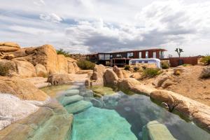 a resort with a swimming pool in the middle of rocks at Iconic 7,000sf Glass Villa with 2 Pools on 350 Acres in Pioneertown