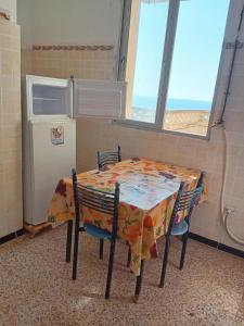 a table with two chairs and a refrigerator in a room at Appartement avec terrasse Vu sur mer in Rebaïb