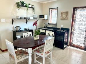 a kitchen with a wooden table and white chairs at Thyme Inn on Greenway in White River