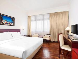 a hotel room with a large bed and a television at MMUGM Hotel in Yogyakarta