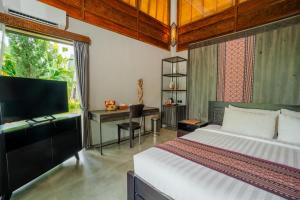 a bedroom with a bed and a desk and a television at MAHALAYA Garden Resort in Pablengan