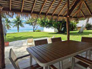 a wooden table and chairs under a wooden umbrella at Hôtel Atiapiti in Opoa