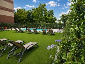 a group of chairs sitting on the grass near a swimming pool at voco Madrid - Las Tablas by IHG in Madrid