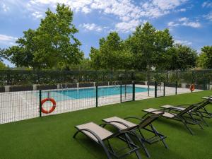 a group of chairs sitting next to a swimming pool at voco Madrid - Las Tablas by IHG in Madrid