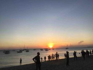 a group of people standing on the beach watching the sunset at Tonys homestay in Zanzibar City +20 photos