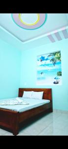 a bed in a room with a painting on the wall at 846 A12 Bùi Thiện Ngộ in Cù Lao Tâu