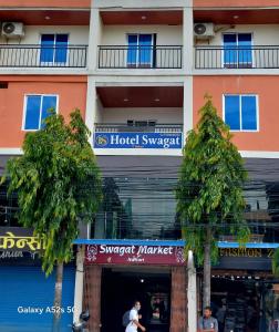 a hotel with trees in front of a building at Hotel Swagat in Itahari