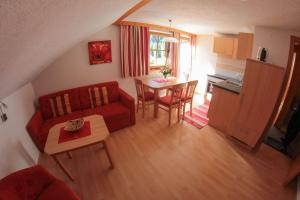 ein Wohnzimmer mit einem roten Sofa und einem Tisch in der Unterkunft Apartments Biobauernhof Lercher in Sankt Jakob in Defereggen