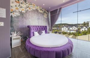 a purple bed in a room with a large window at Mac Valley DaLat Hotel in Da Lat