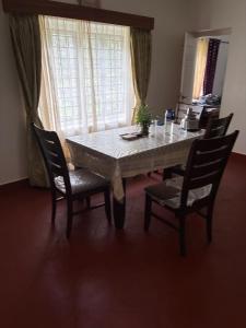 a dining room table with chairs and a table and a window at Springdale Villa in Kodaikānāl