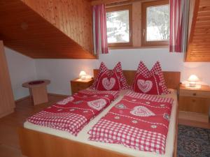 Schlafzimmer mit einem Bett mit roten und weißen Kissen in der Unterkunft Apartments Biobauernhof Lercher in Sankt Jakob in Defereggen