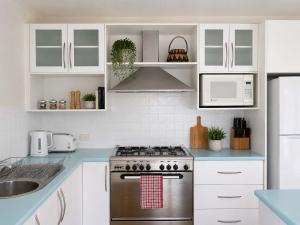 a kitchen with white cabinets and a stainless steel stove at The Coastal Haven in Manyana